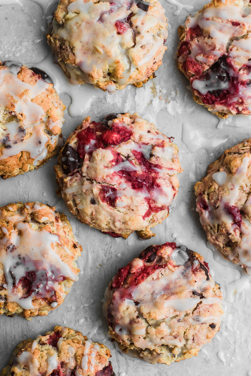 Roasted strawberry chocolate oat scones on white background drizzled with glaze.