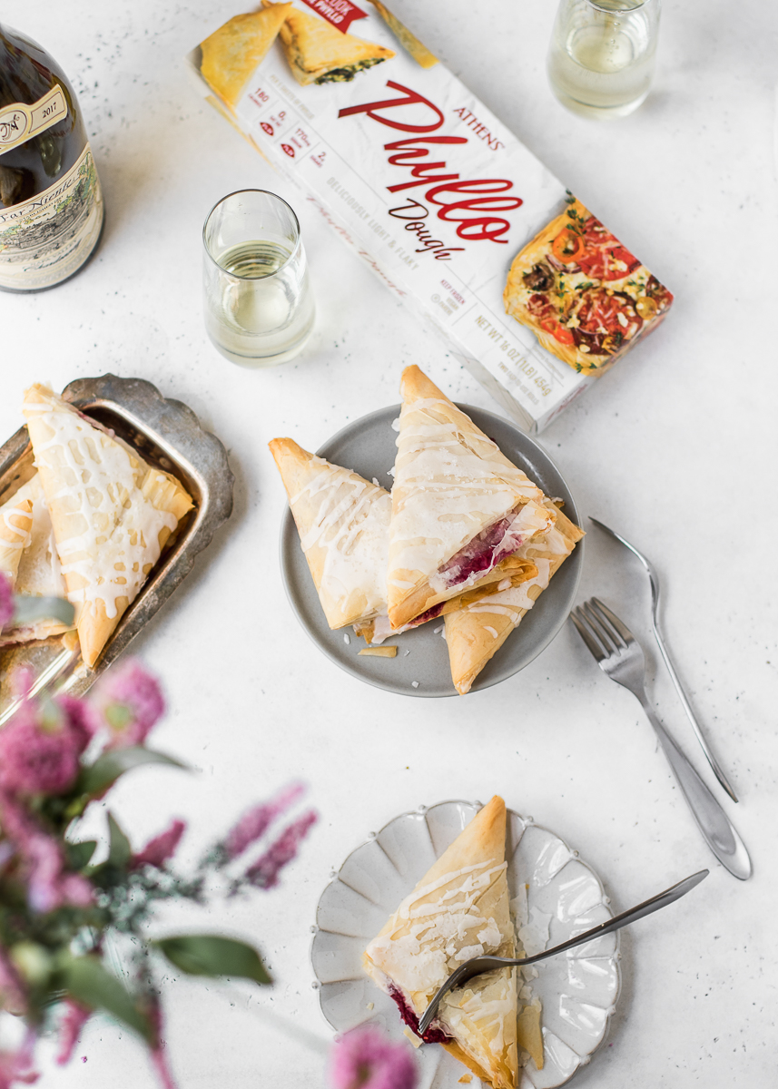 Flat lay on white background with phyllo dough, wine and raspberry turnovers.