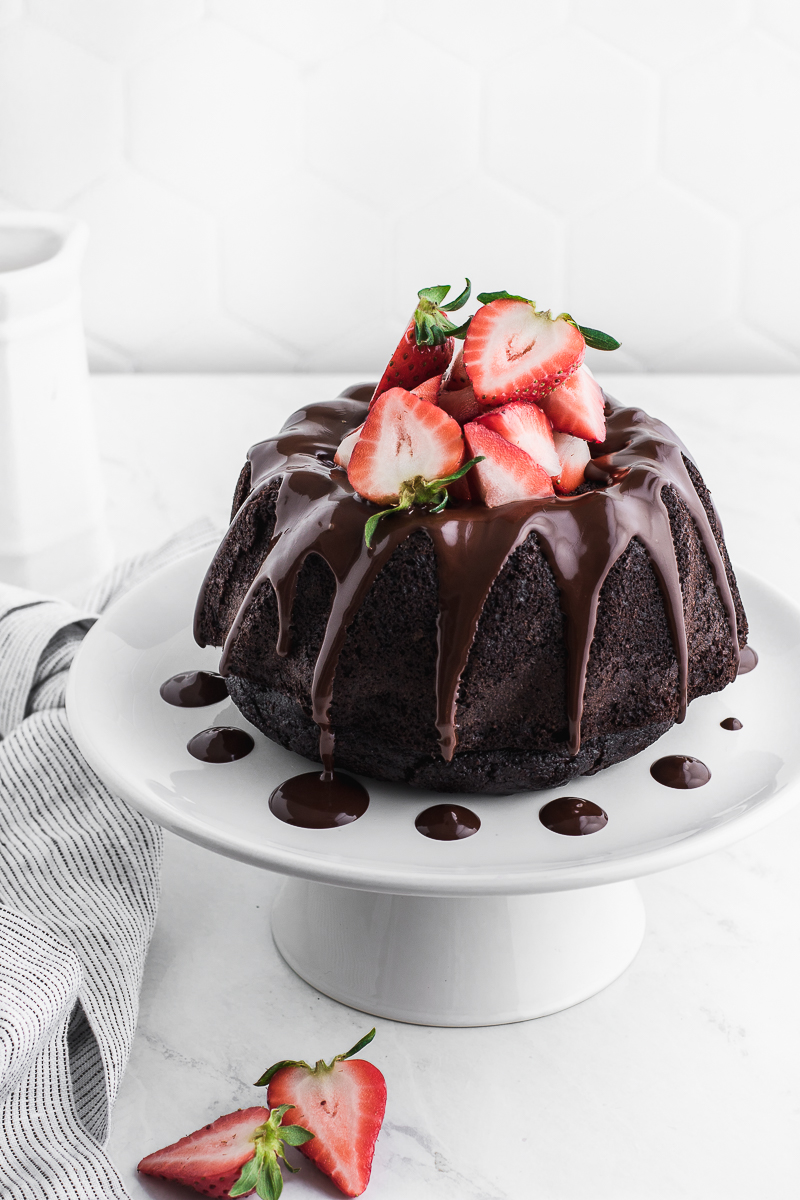 chocolate drizzle running down a chocolate bundt cake with strawberries