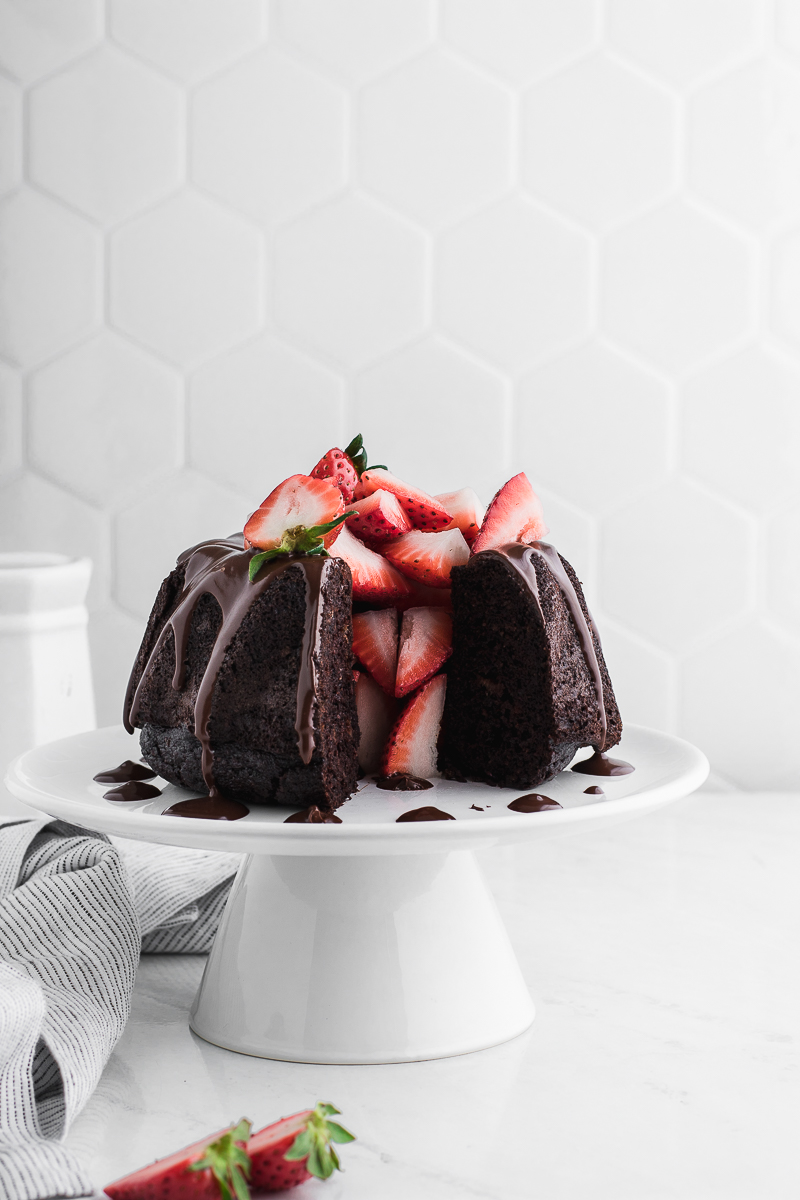 chocolate bundt cake with chocolate drizzle and strawberries with missing cake piece