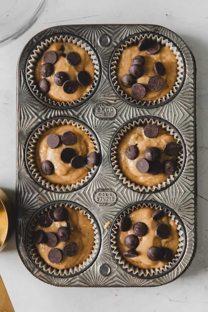 chocolate chip muffin batter in pan with chocolate chips on top before baking