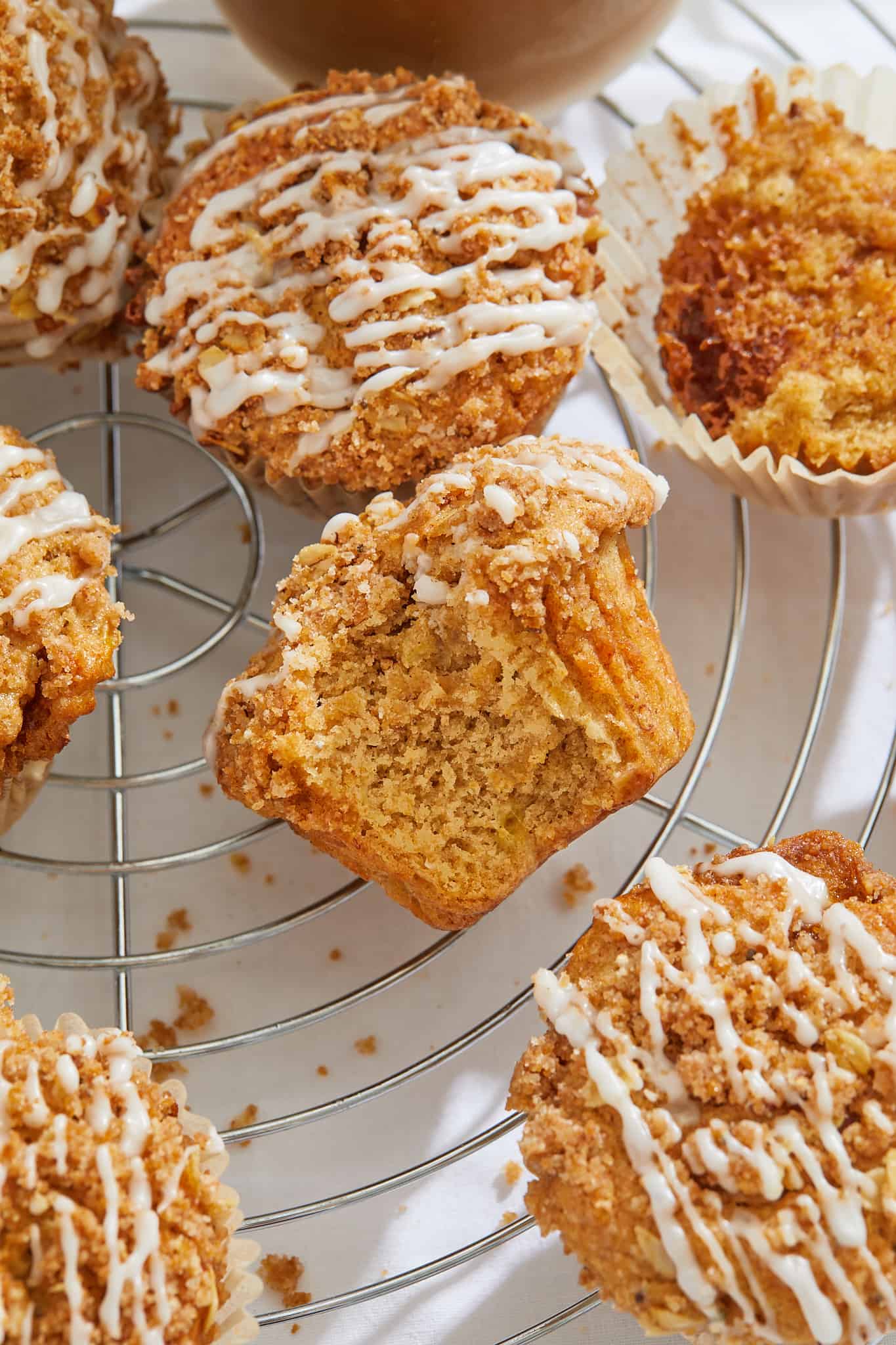 cinnamon streusel muffins with sweet glaze on a cooling rack