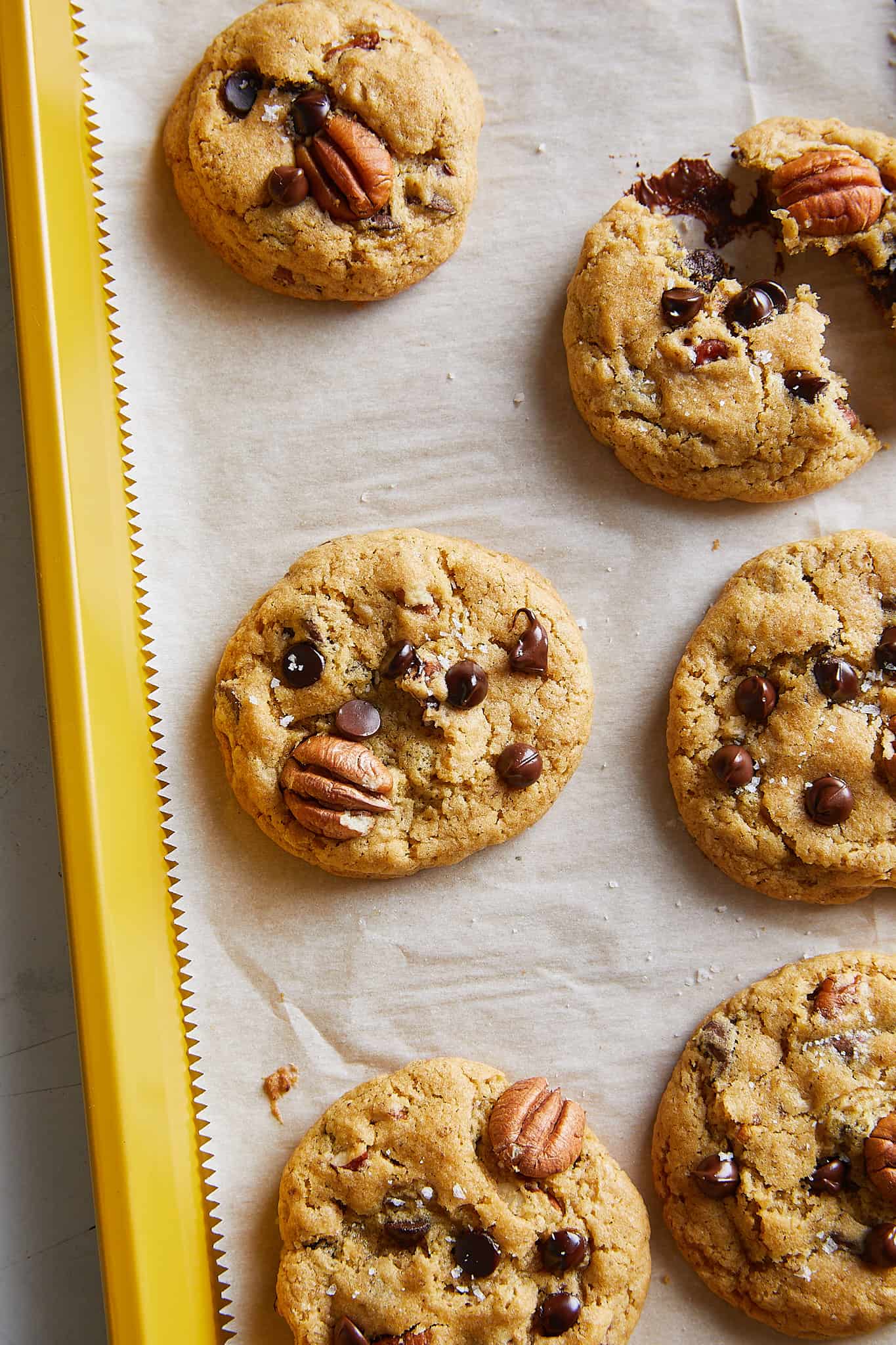 chocolate chip pecan cookies on a yellow baking sheet