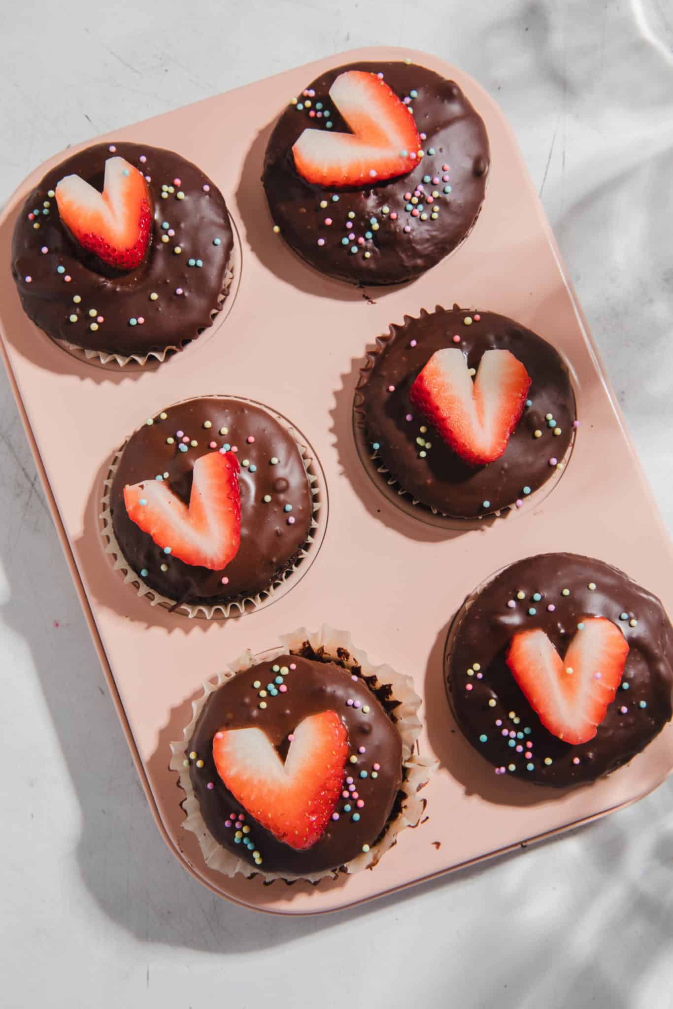 gluten free cupcakes in a pink tin with chocolate ganache and strawberries