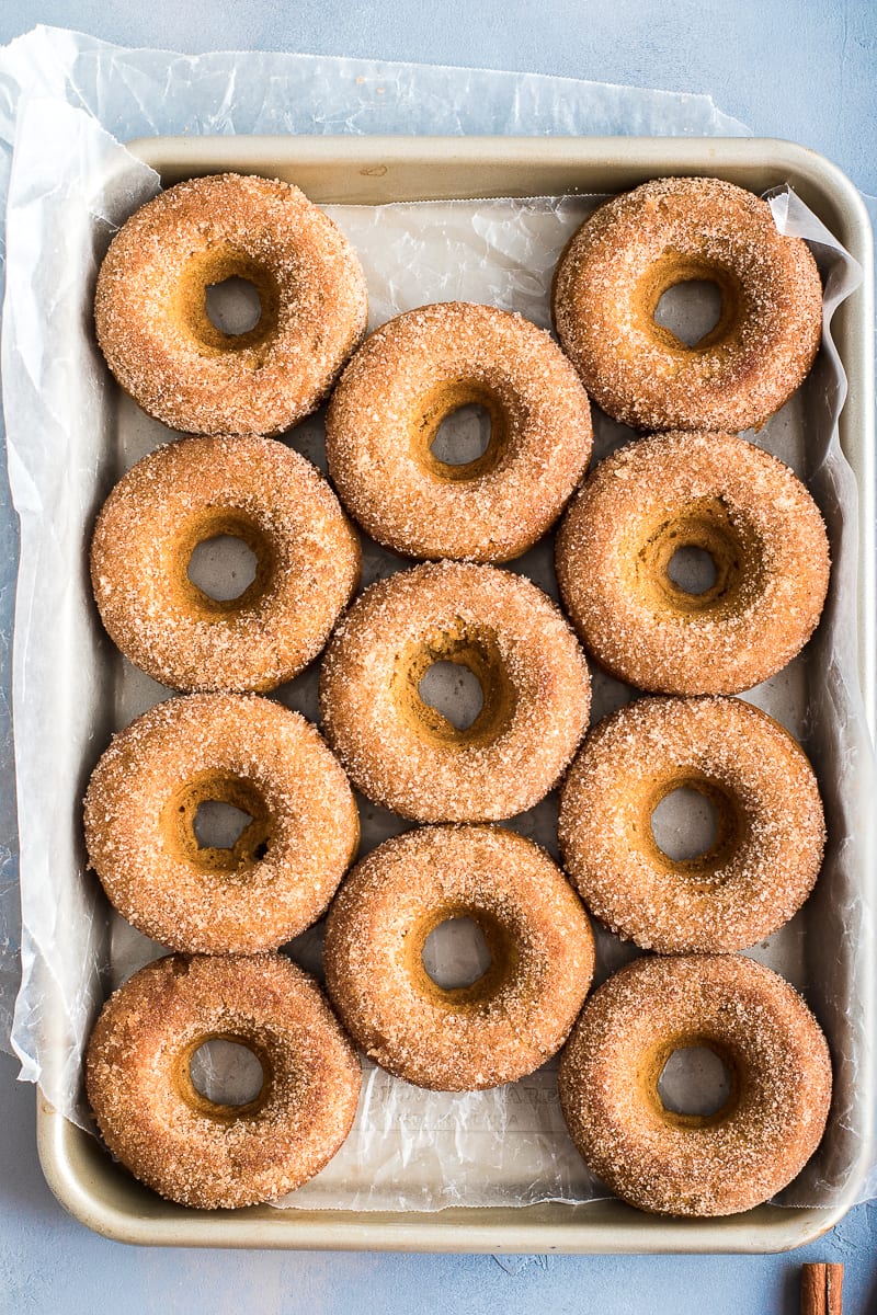 pumpkin protein donuts in a pan with cinnamon sugar