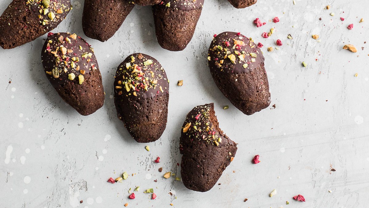 Chocolate dipped madeleines with crushed pistachios and raspberries.