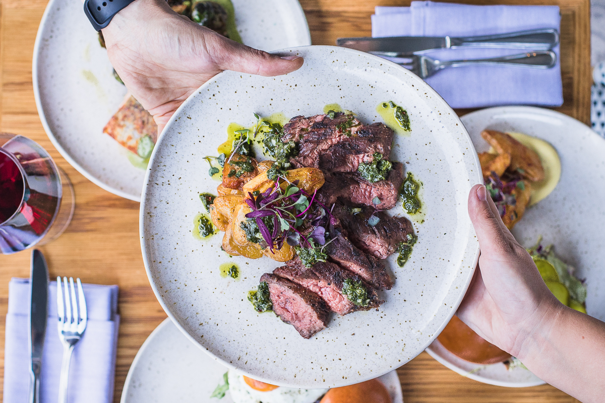 restaurant photography hands holding plate of steak