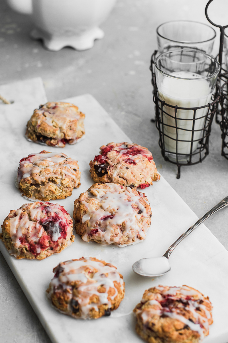 Roasted strawberry chocolate oat scones on white background drizzled with glaze.