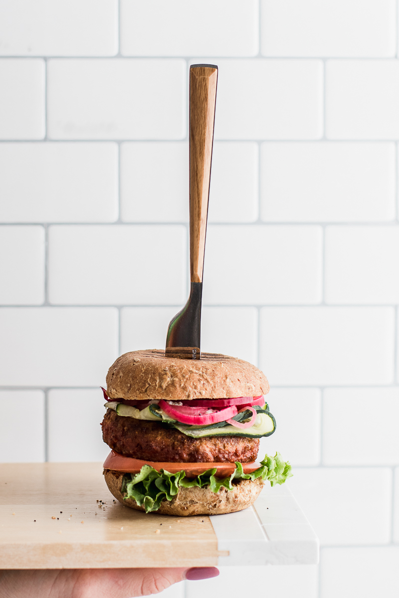 Burger being held out on cutting board