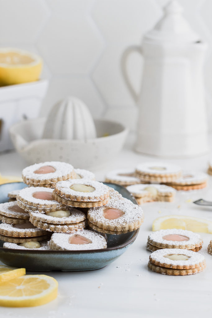 linzer cookies stacked on blue plate with lemons