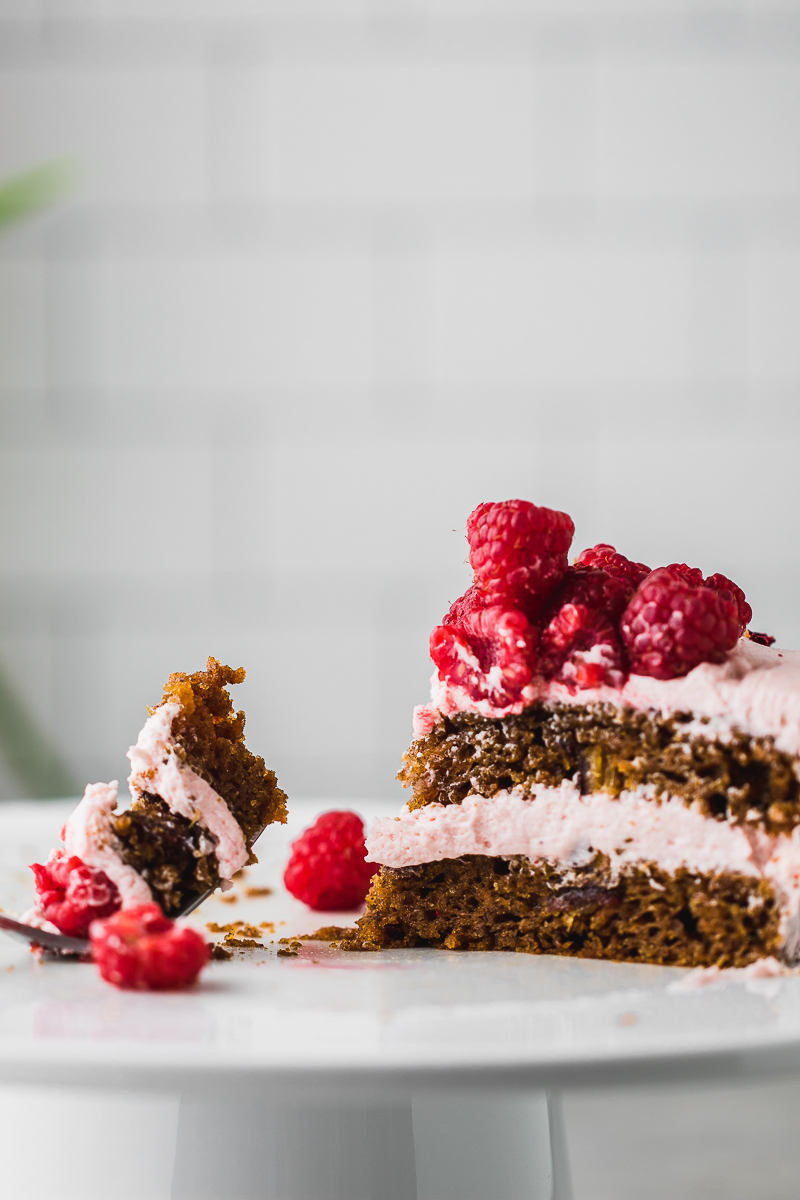 one slice of carrot cake with raspberries and fork taking a bite