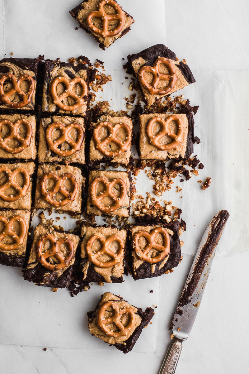 brownies with peanut butter and pretzels on white flat lay