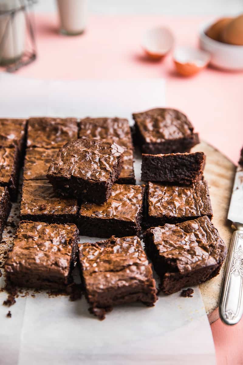 Thick fudgy chocolate brownies cut into squares on pink backdrop