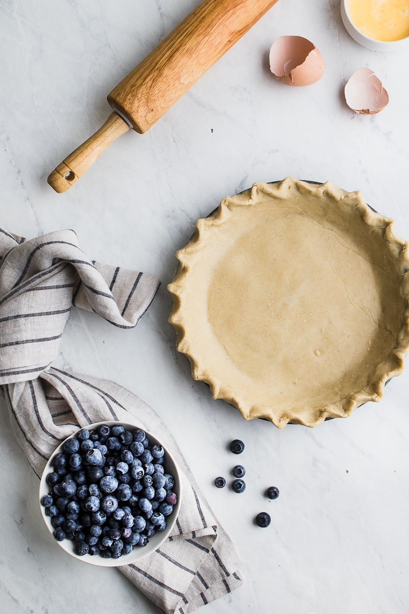 gluten free pie crust flat lay with rolling pin and egg shells