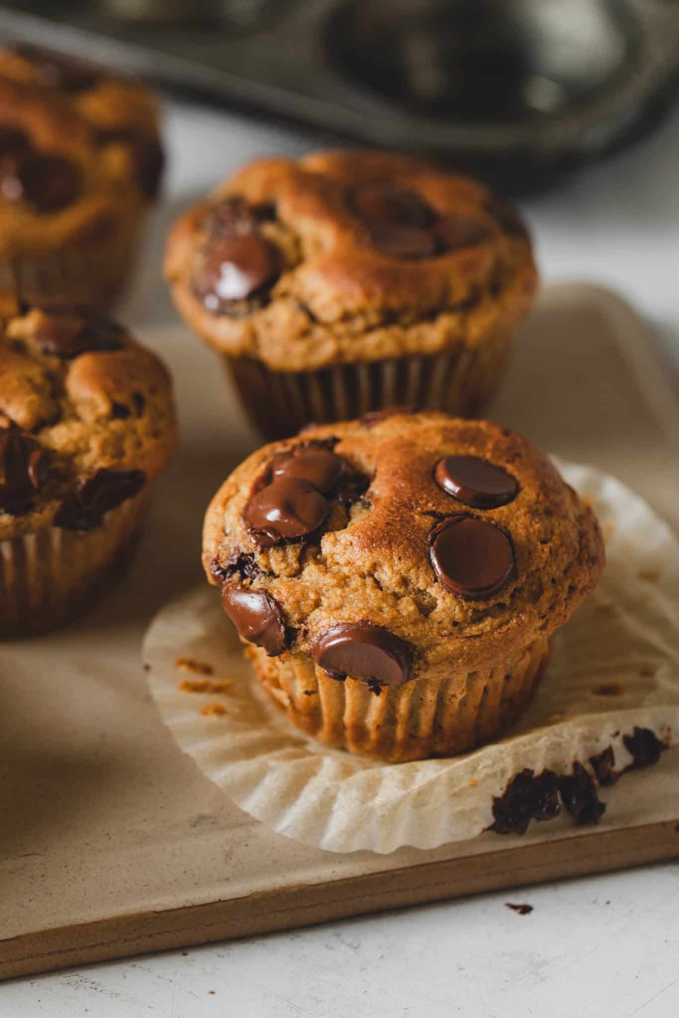 Healthy chocolate chip muffins with liner removed and glistening chocolate chips on top.