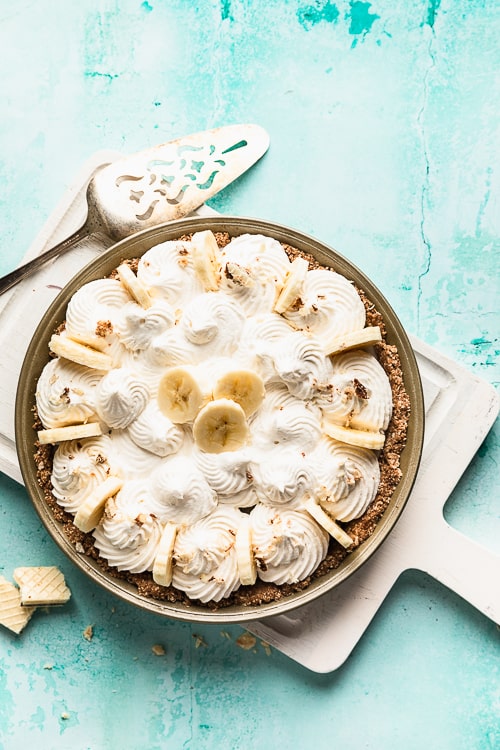 A perfect dairy free banana cream pie on a white cutting board and aqua surface.