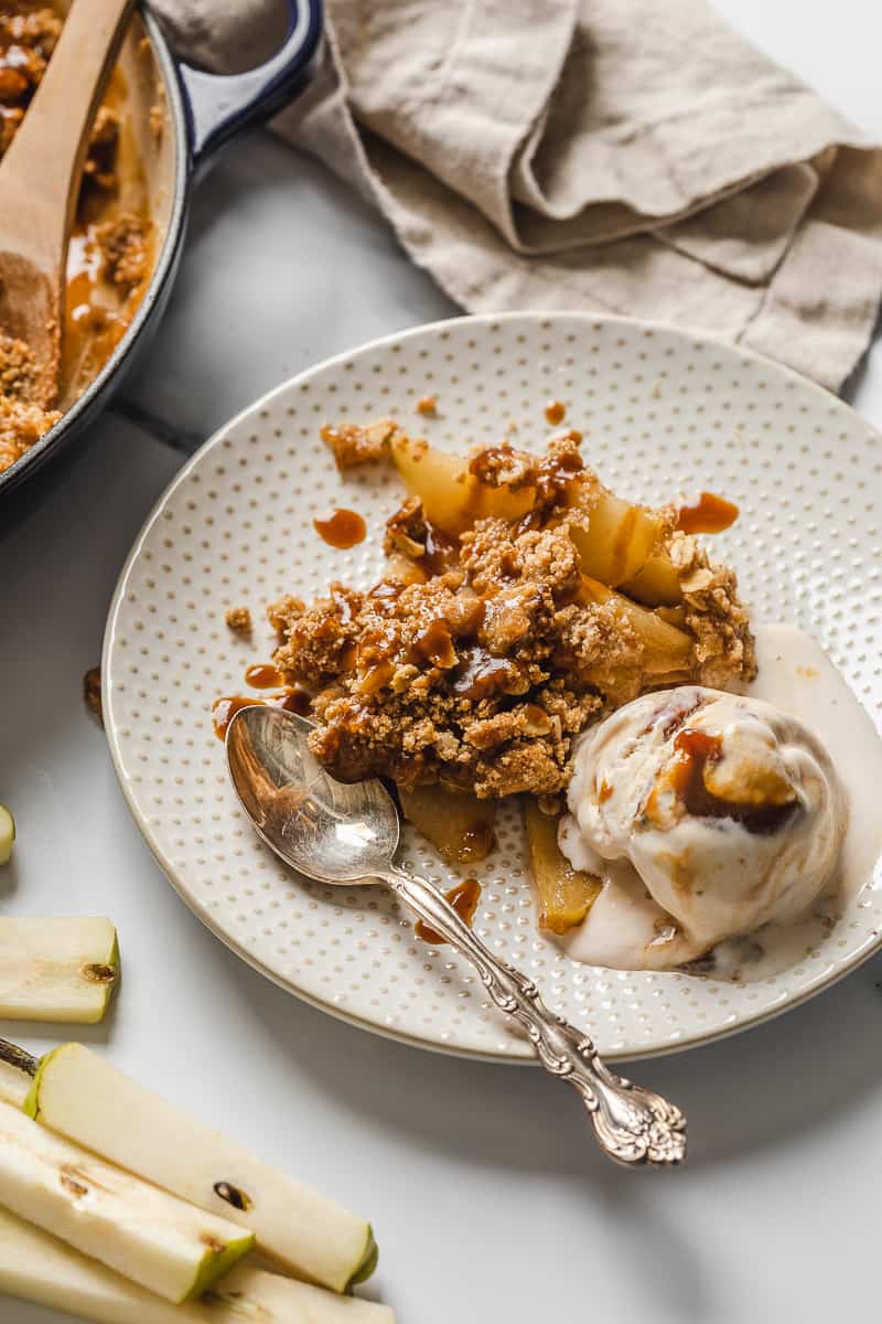 Easy vegan pear crisp with oats made gluten free and dairy free.  Topped with caramel sauce and ice cream.