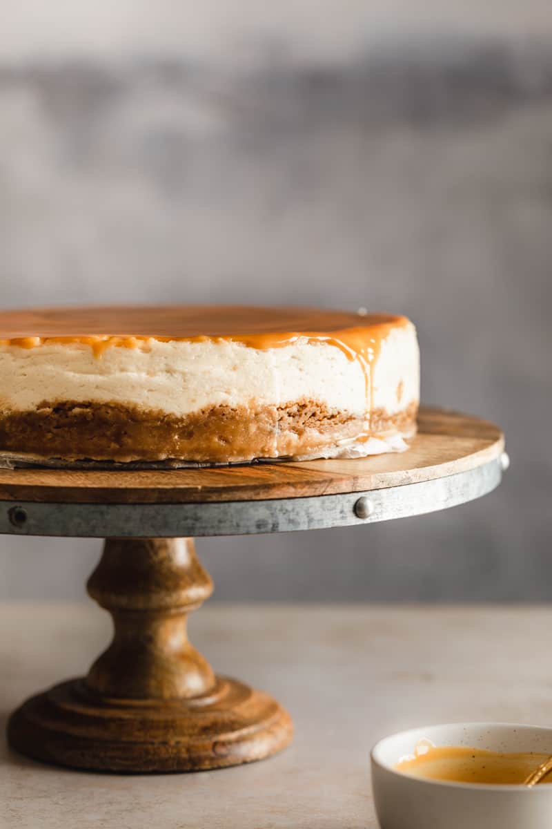Vegan caramel cheesecake on a cake stand with caramel dripping