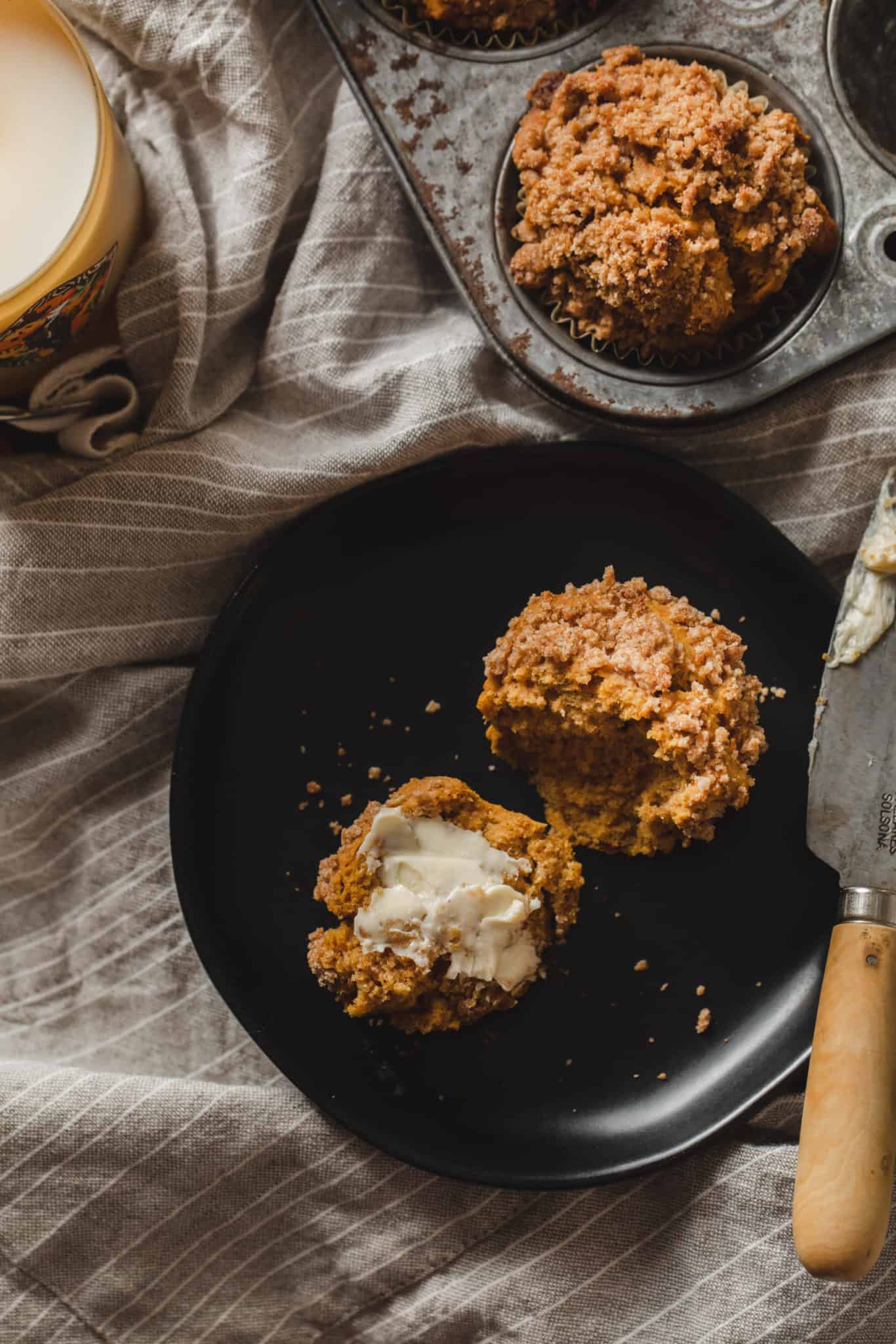 A vegan pumpkin muffin recipe with crumble topping  some butter sitting on a plate 