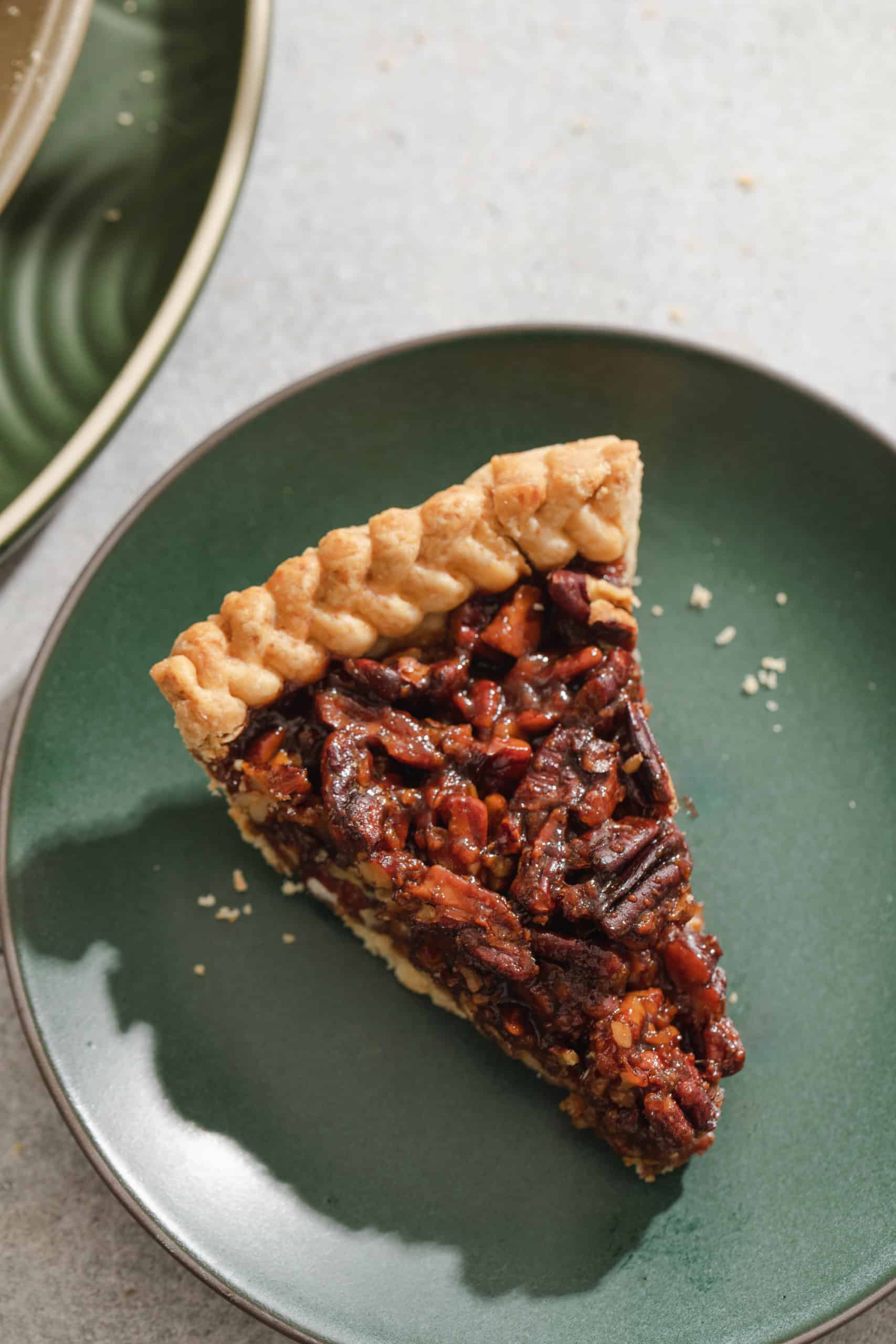 a slice of vegan pecan pie on a green plate