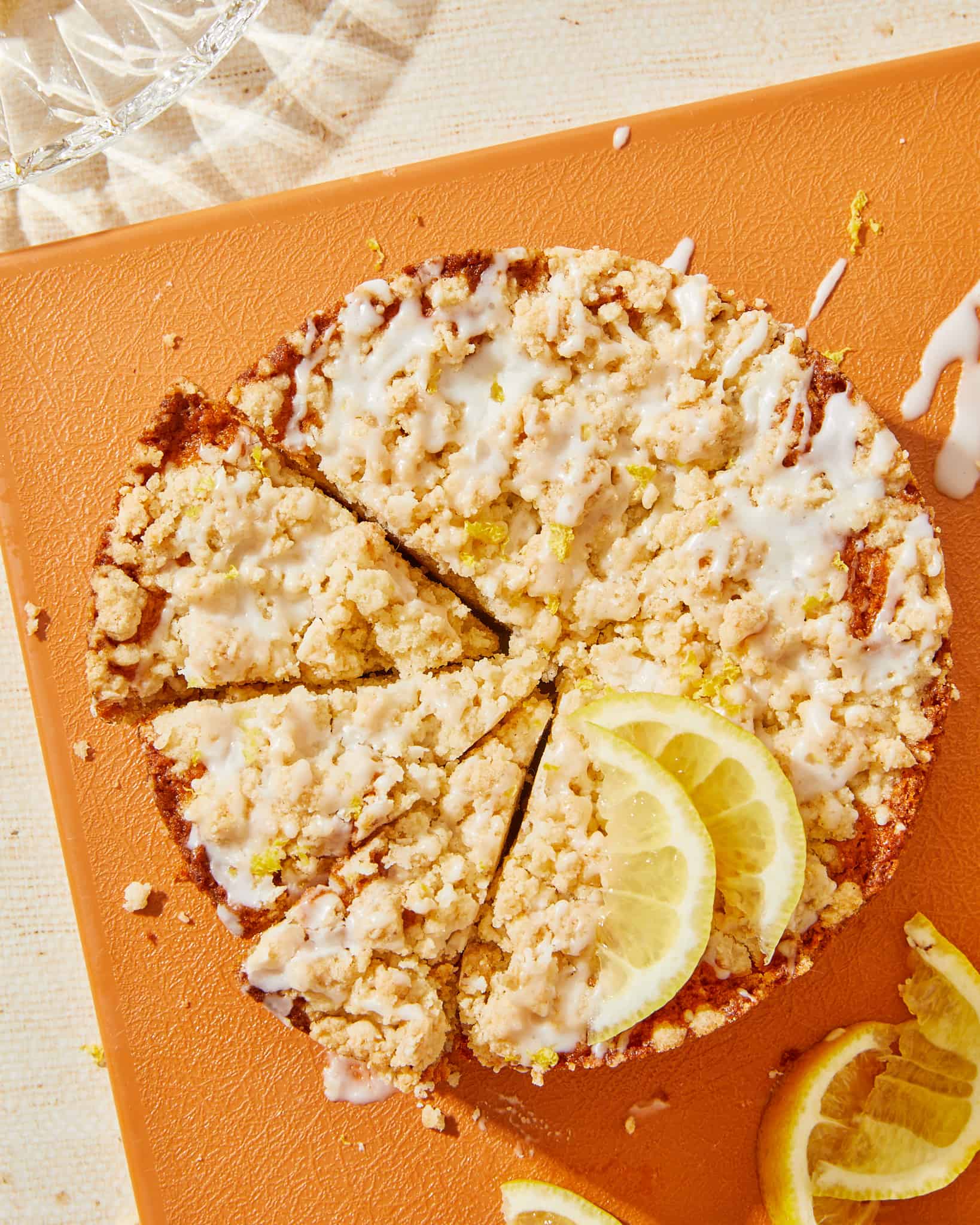 Vegan lemon crumb cake cut into slices on orange cutting board