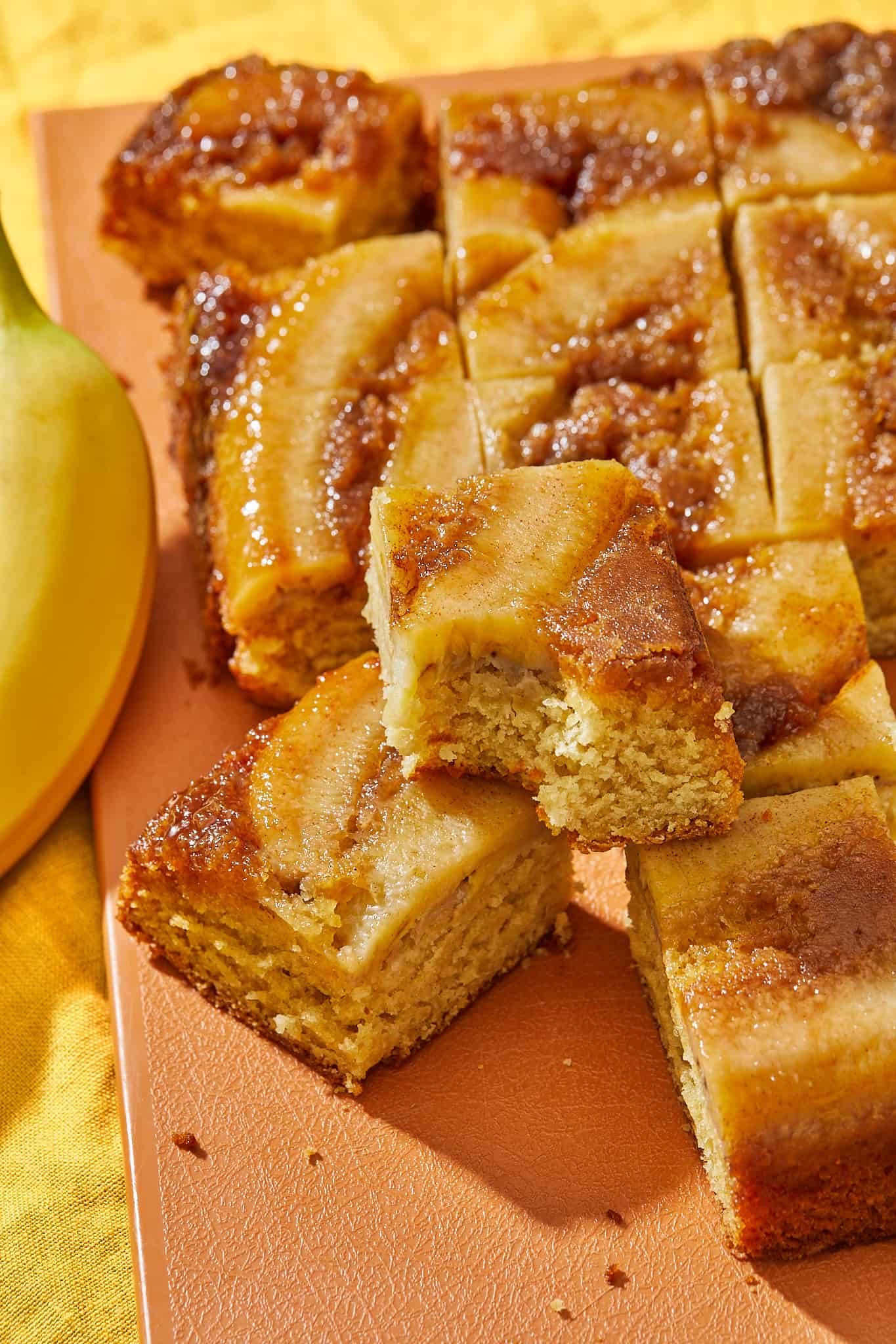 A gooey caramelized banana upside down cake with slices cut out.