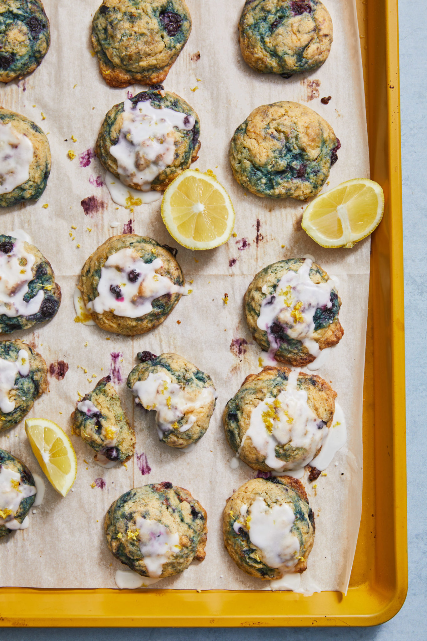 lemon blueberry cookies on a yellow baking tray with glaze
