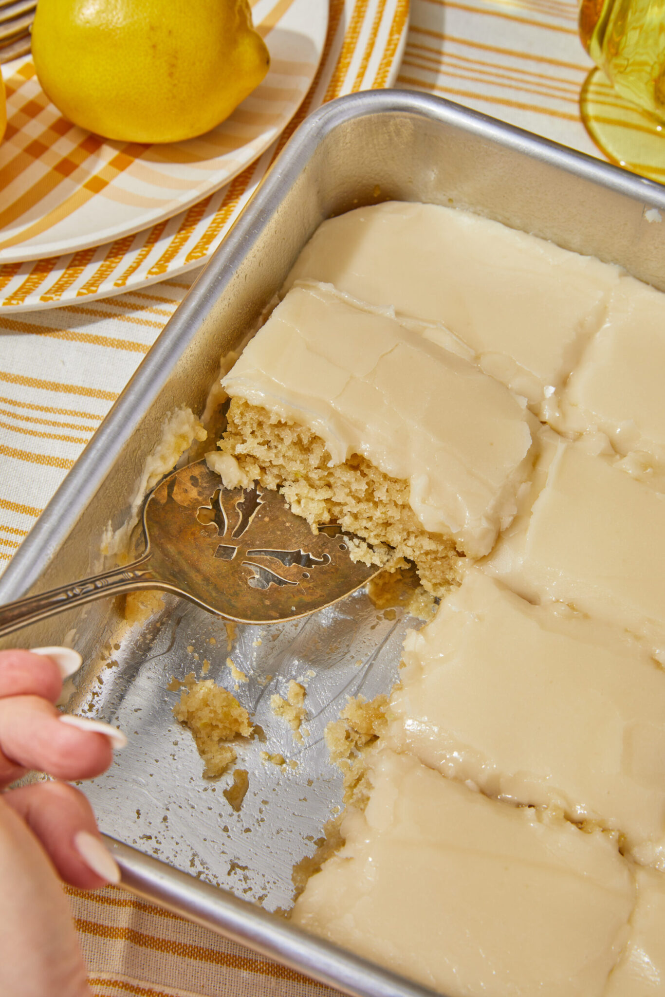 a piece of vegan lemon drizzle cake being taking out of the pan