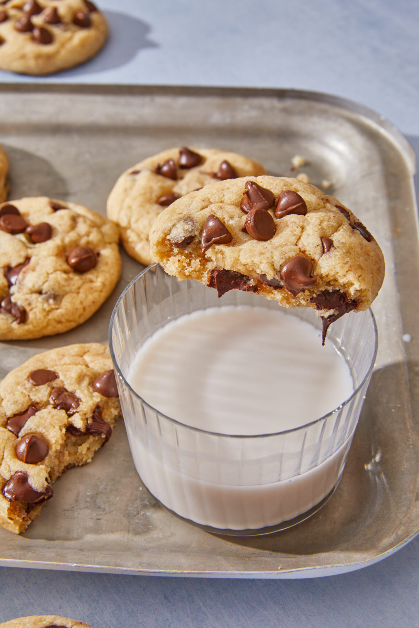 chocolate chip cookies without brown sugar broken in half on top of a cup of milk
